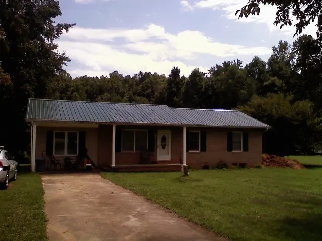 Dark green metal roof on a brick ranch with a covered porch in White Sulphur Springs