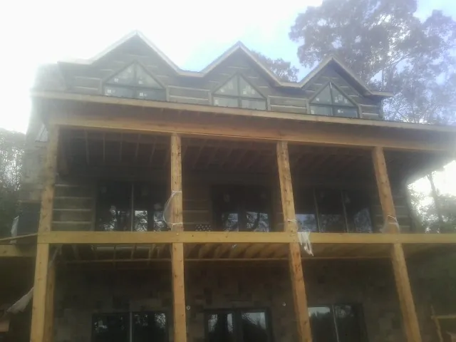 Dormers and porch framing on a large log home under construction — Roof Coating work by our crew in White Sulphur Springs