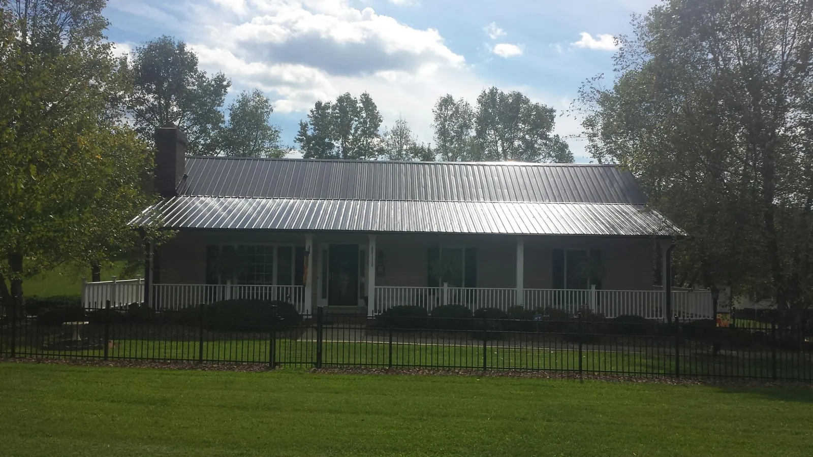 Gray metal roof on a brick ranch with a full width front porch — Gutter Guard Installation work by our crew in White Sulphur Springs